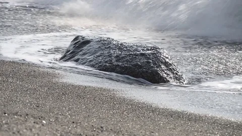The waves break on the beach early in the day and flood stones on the shore Stock Footage 84009808