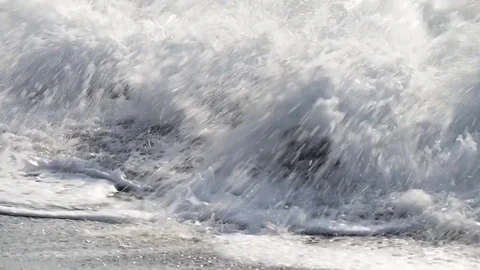 The waves break on the beach early in the day and flood stones on the shore Stock Footage 84011785