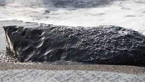 The waves break on the beach early in the day and flood stones on the shore Video stock 84012421