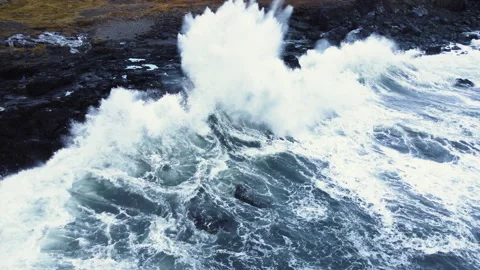 Waves break on black volcanic rocks in a blue ocean, Storm in sea Aerial view Stock Footage