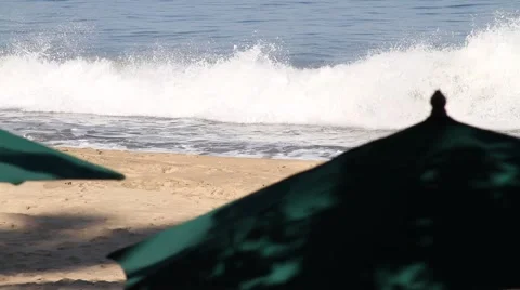 Waves break in front of beach umbrella Stock Footage 947892