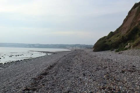 Waves break gently on to the pebble beach at Axmouth in Devon. Stock Photos