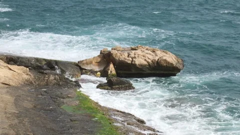 Waves break over algae covered shoreline rocks green tinged stone tidal texture Stock Footage 341800331