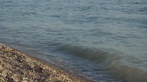 Waves break on a pebble beach at sunset. Stock Footage 150580677