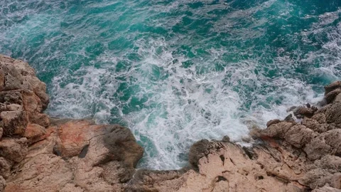 The waves break on the rocks. Clear sea water . Top down view from the cliff  Stock Footage 169666046
