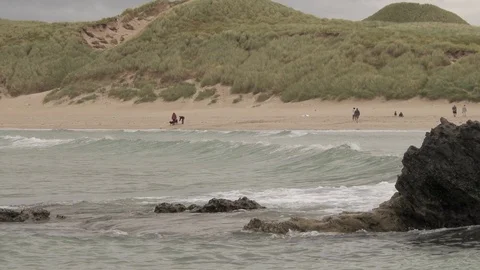 Waves break on the rocks with people on the beach 2 4K-Scotland sea Stock Footage 94869349