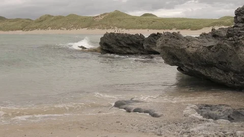 Waves break on the rocks with people on the beach 2 4K-Scotland sea Video stock 94869720