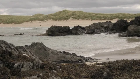 Waves break on the rocks with people on the beach 3 4K-Scotland sea Video stock 94870415