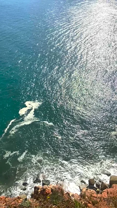 Waves break on the rocky shore. Waves break on big rocks on the shore on a sunny Stock Footage 312803677
