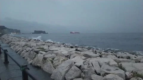 Waves break on the seafront of Mergellina with the Castel dell'Ovo in Naples Stock Footage 221830447
