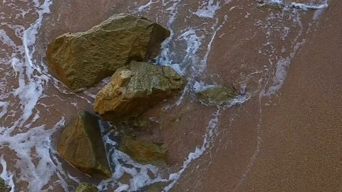Waves break on stones. A shot of rough water on a rocky ocean coastline near Stock Footage 78988109