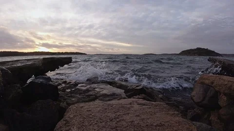 Waves breaking against a broken stone pier at sunset Stock Footage 145870783