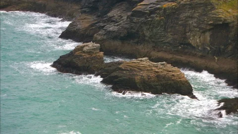 Waves breaking against rocks of coast with sea behind Video stock 95604775
