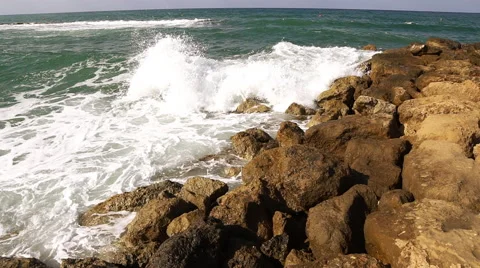 Waves breaking against rocks on sea shoreline. Видео 68046606