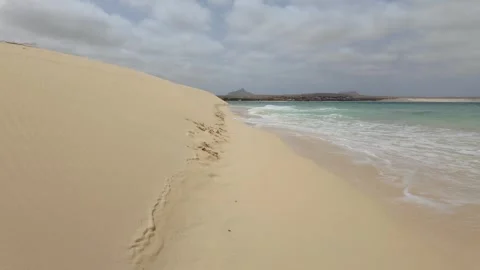 Waves breaking against sand dunes as they meet the sea on the shoreline of .. 스톡 동영상 319987960