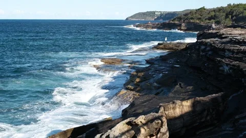 Waves breaking along rugged rocky Australian coast on sunny day Stock Footage 317977304