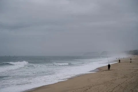 Waves breaking along sandy beach under cloudy sky in Santa Cruz Portugal Stock Photos