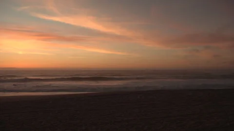 Waves breaking on beach at dusk with golden orange sky, Stock Footage 331755116