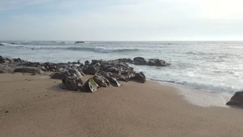 Waves breaking on beach with rocks on shore, slow motion. Stock Footage 194200066