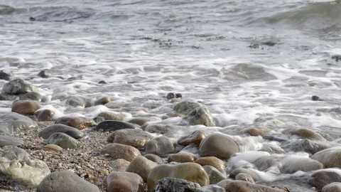 Waves breaking on a beach with round stones Stock Footage 128985968