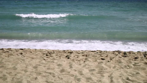 Waves breaking on beach on a sunny day Stock Footage 229618340
