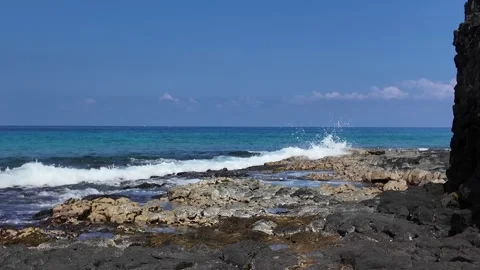 Waves breaking on a black lava rock coast with deep blue sea in Hawaii 動画素材 347826286
