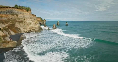 Waves breaking on coastal landscape with large sea stack columns, aerial Stock Footage 265220629