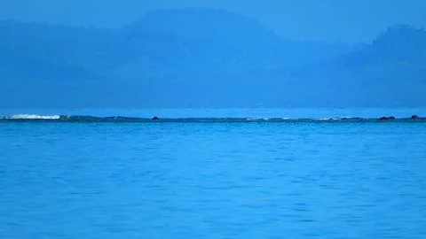 Waves breaking on distant reef with hazy island backdrop Stock-Fotos