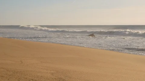 Waves breaking on an empty, misty, sandy beach in the morning. Slow slide right. Stock Footage 103280532