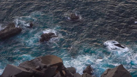 Waves breaking erosion eroding dark basalt rocks near shore. Stock Footage 110761665