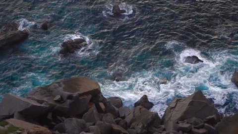 Waves breaking erosion eroding dark basalt rocks near shore. Stock Footage 110761824