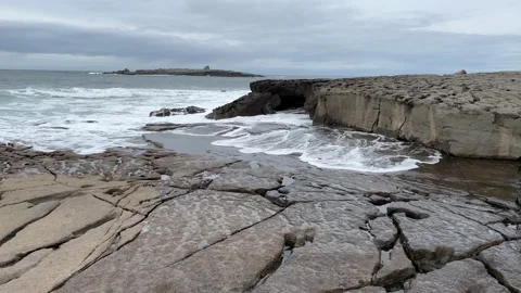 Waves Breaking Onto Flat Stone With Island In Background Stock Footage