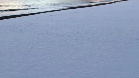 Waves breaking gently on snowy beach on a winter morning Stock Footage 319574688