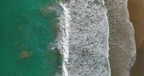 Waves breaking onto a golden sandy beach Stock Footage 343622628