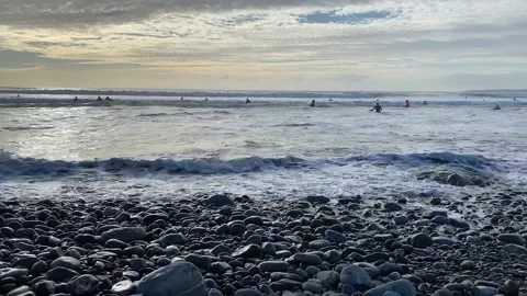 Waves breaking on kinsale surfers Stock Footage 153990613