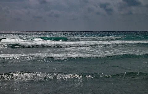 Waves breaking onshore beneath a stormy sky Stock-Fotos