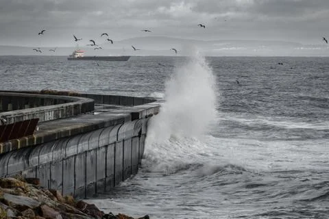 Waves breaking over breakwater Photos