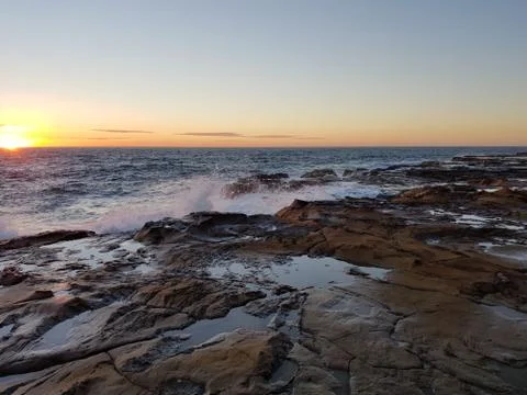 Waves breaking over rocks at the beach. Stock Photos