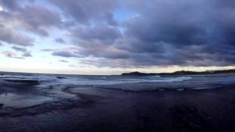 Waves breaking over rocks, with clouds passing overhead. Видео 75769185