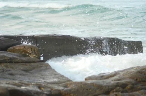 Waves breaking over a rocks, creating white water. Stock Photos