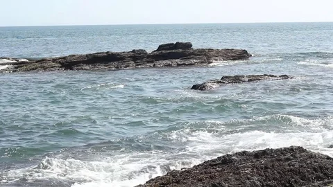 Waves breaking over rocks on sunny sea near coast Stock Footage 73275209