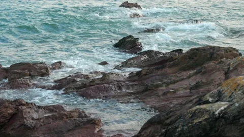 Waves breaking over rugged rocks in slow motion Stock Footage 165346760