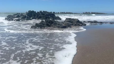 Waves breaking over sandy beach rock on hot summer day Stock Footage 272578510
