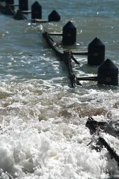 Waves breaking over the wooden posts of ocean baths. Stock Photos