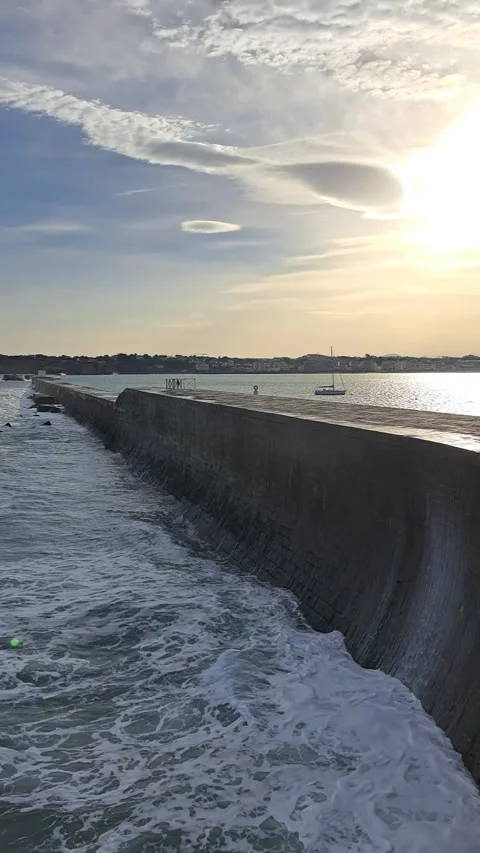 Waves breaking on a pier with sun setting Stock Footage 315601864