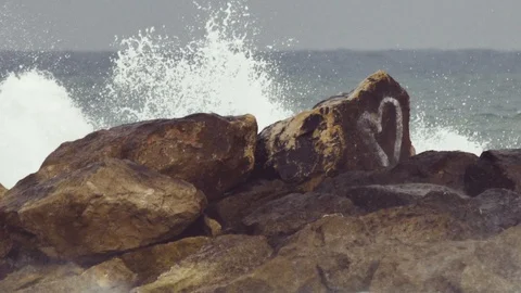 Waves breaking on rocks with a heart graffiti slowmotion Stock Footage 90084496