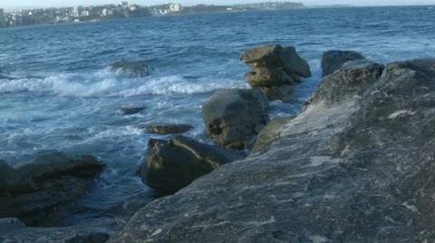 Waves breaking on rocks at Manly Beach while a ski boarder passes by. Stock Footage 68341343