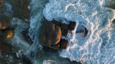 Waves breaking on rocks on the shore of the beach at sunset Stock Footage 201731000