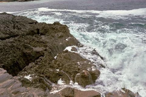 Waves breaking on the rocks at the shore of the beach Stock Photos