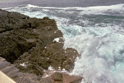 Waves breaking on the rocks at the shore of the beach Stock Photos